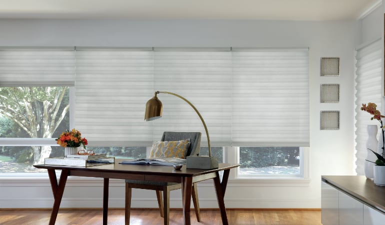 Motorized shades can be opened or closed with the quick push of a button. Motorized shades in a home office.